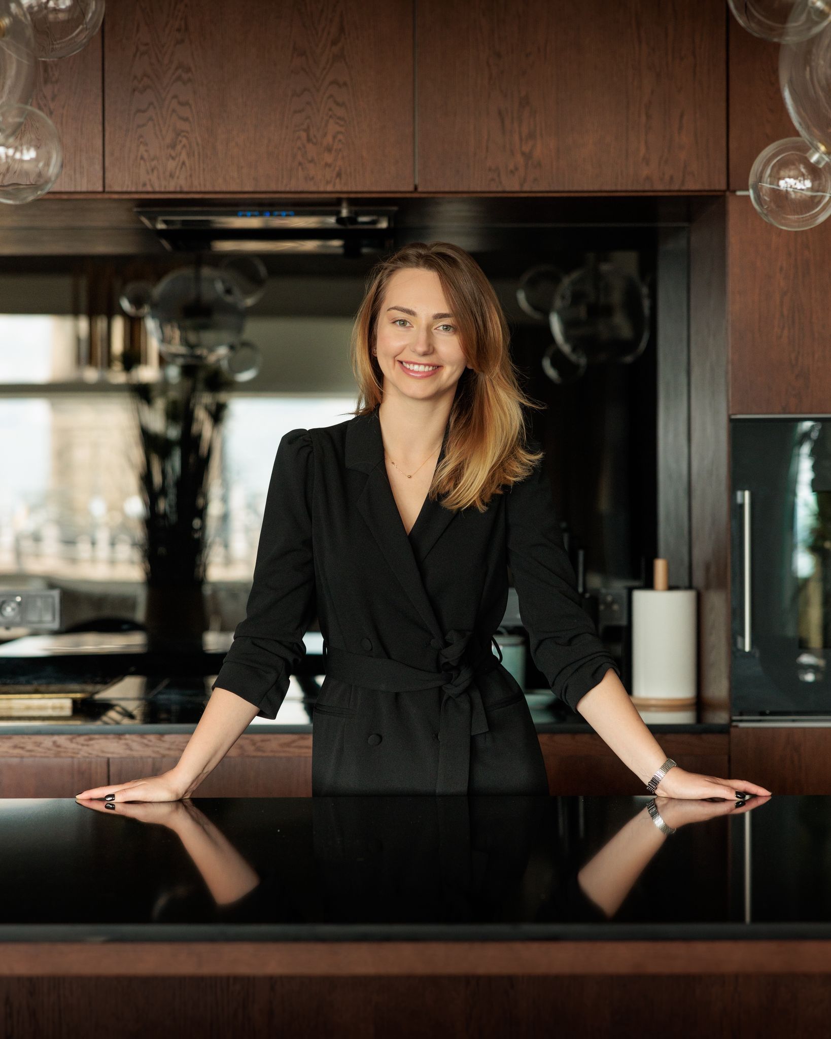 Anastasia Goluk stoi przy ciemnym blacie kuchennym w czarnej marynarce
